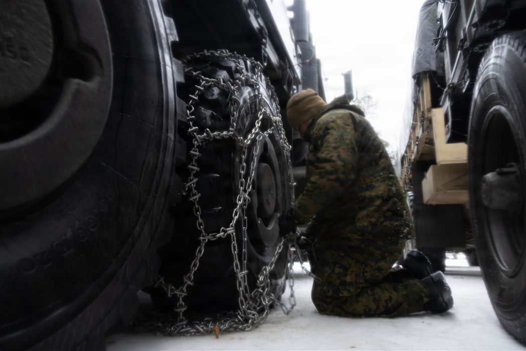 Marine attaching tire chains to logistics vehicle during Arctic cold weather operations
